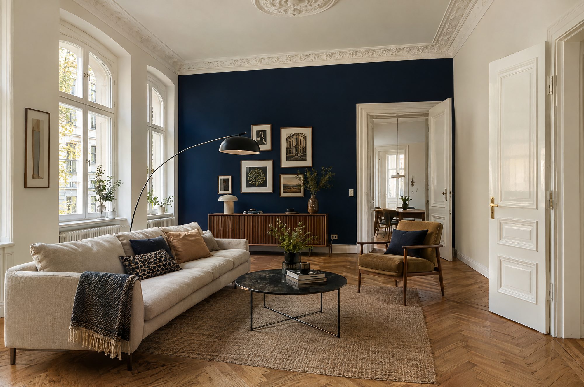 Altbauwohnzimmer mit dunkelblauer Akzentwand und weißem Stuck